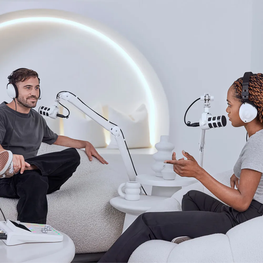 Two podcasters recording with white RØDE PodMics